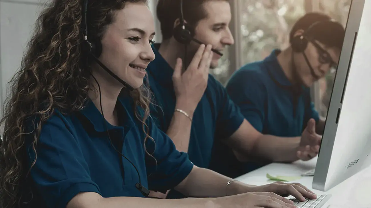 Cheerful looking people with headsets at desks answering calls and making outbound calls