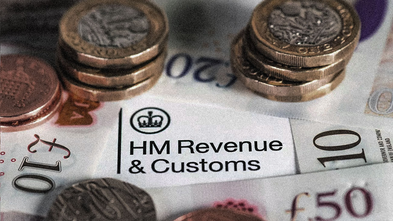 Paper and coin money spread around a paper with printed HM Revenue & Customs and logo