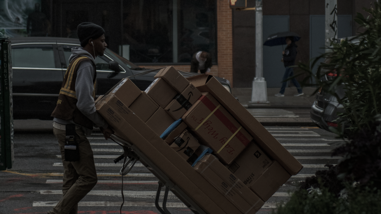A man with a large cart delivering many different size packages and cardboard boxes