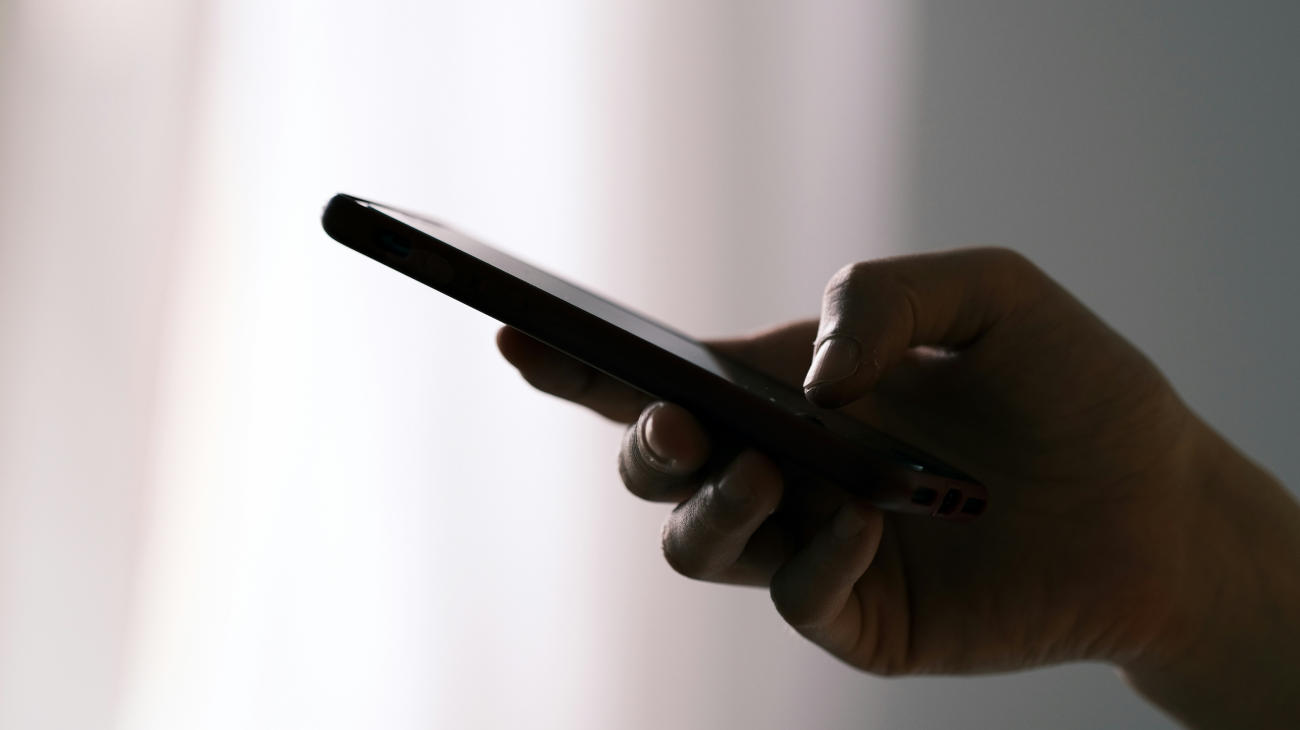 A person holding out their mobile phone where there could be a scammer trying to initiate a call